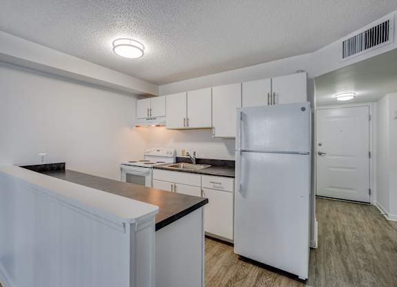 a kitchen with white cabinets and a white refrigerator