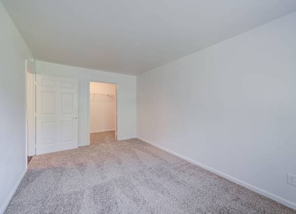a bedroom with a carpeted floor and a door to a closet at Carolina Springs Apartments, Carrboro, NC  