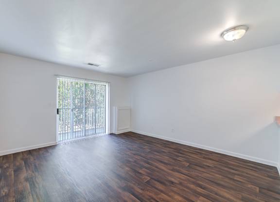 an empty living room with wood flooring and a sliding glass door at Carolina Springs Apartments, Carrboro, North Carolina  