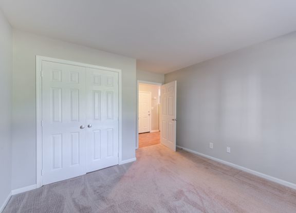 a bedroom with a white door and a large empty room at Carolina Springs Apartments, North Carolina  