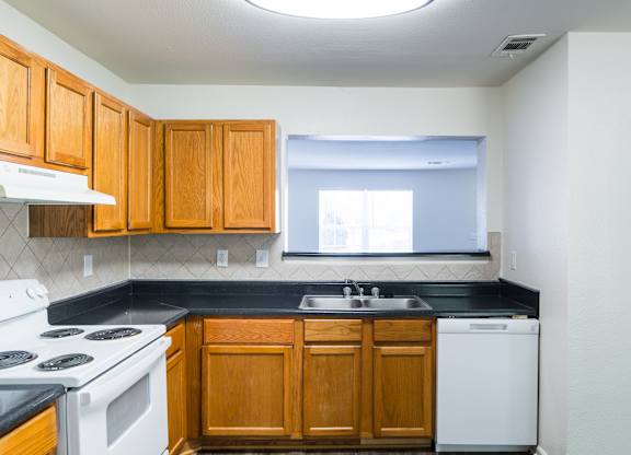 an empty kitchen with white appliances and wooden cabinets at Crescent Pointe Townhomes, Stafford Virginia