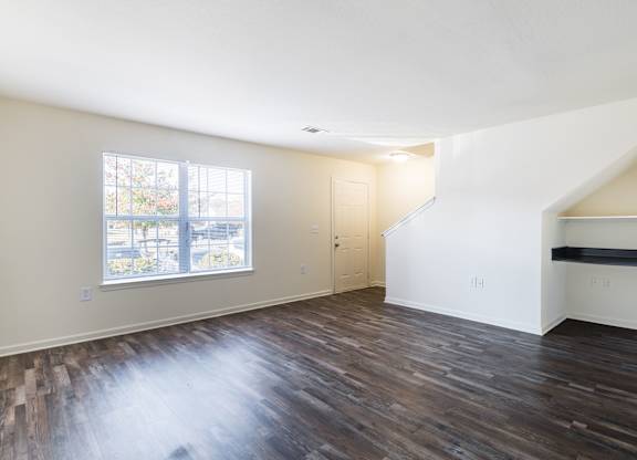 an empty living room with hard wood floors and a window at Crescent Pointe Townhomes, Virginia