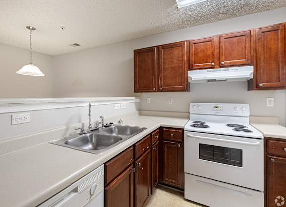 Kitchen with white appliances and wooden cabinets at Cross Creek Apartments, Beaufort, SC, South Carolina, 29906