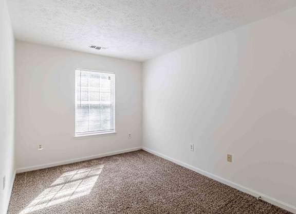 A room with a window and carpeted floor.