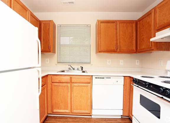A kitchen with wooden cabinets and white appliances at English Oaks Apartments, Virginia