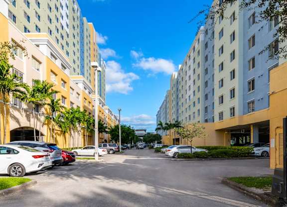 a city street with tall buildings on either side and cars parked on the side of the street