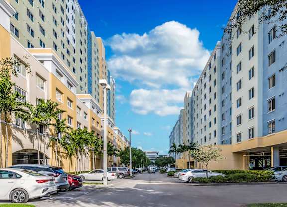 a city street with tall buildings on either side and cars parked on the side of the street