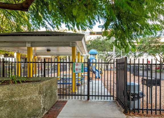 a park with a playground and a gated entrance