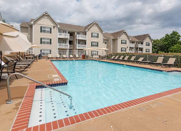 A swimming pool with a red brick border and a building in the background.at Summerland Heights, Woodbridge, 22191  
