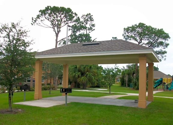 a pavilion with a playground and trees in a park