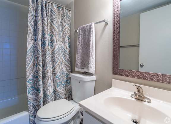 A white toilet sits next to a sink in a bathroom.at Bradley Square, North Charleston South Carolina