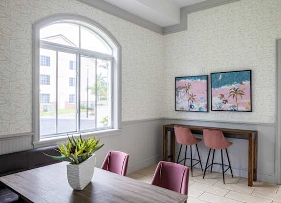 a dining room with two paintings on the wall and a wooden table with pink chairs