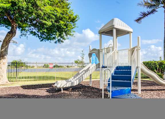 A playground with a white tower structure and a blue slide.
