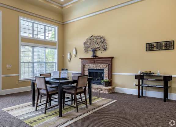 a dining room with a table and chairs in front of a fireplace at Magnolia Lake Apartments, Carrollton, Georgia