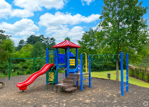 a playground with a red slide and blue playset at Magnolia Lake Apartments, Georgia`