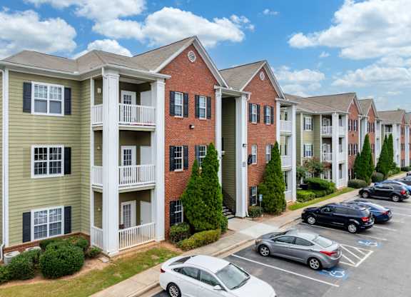 a row of apartment buildings with cars parked in a parking lot at Magnolia Lake Apartments, Carrollton, GA, 30117