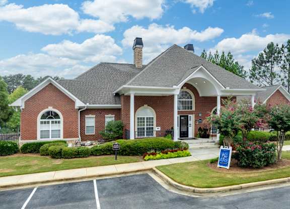 the front of a brick house with a sign in the front yard at Magnolia Lake Apartments, Carrollton, 30117