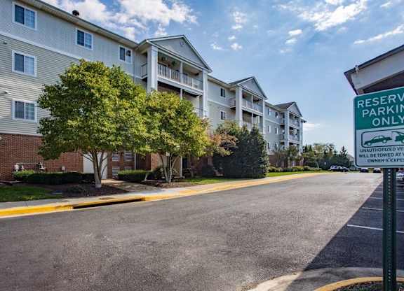 A parking lot in front of apartment buildings with a sign that says 