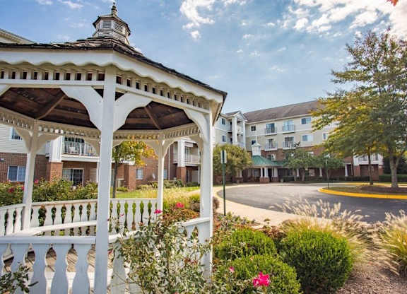 A gazebo is in the foreground of a street with apartment buildings in the background.
