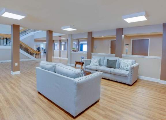 A spacious living room with a grey sofa and wooden flooring.
