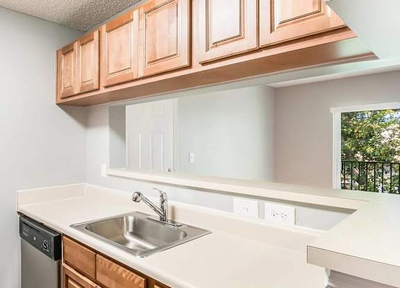 A kitchen with a white counter top and brown cabinets.