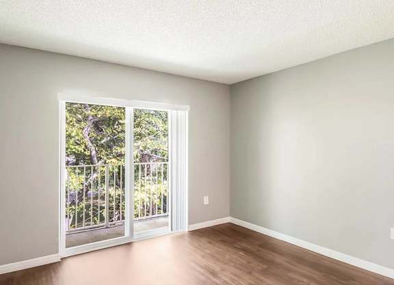 A room with a sliding glass door leading to a balcony.