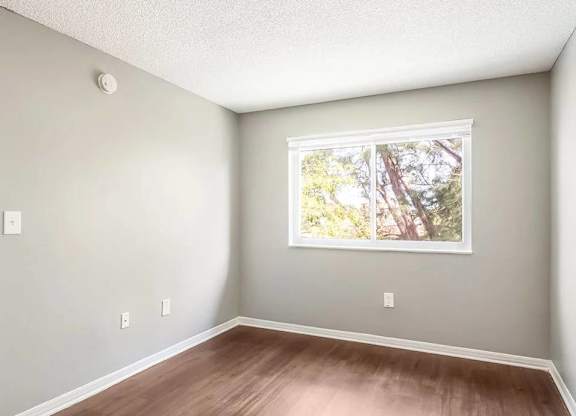 A room with a window and a wooden floor.