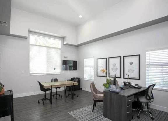 A room with a desk and chairs in front of a window.