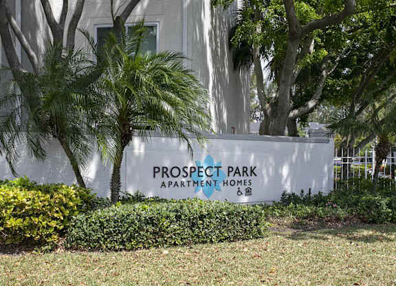 A sign for Prospect Park Apartment Homes stands in front of a building and trees.