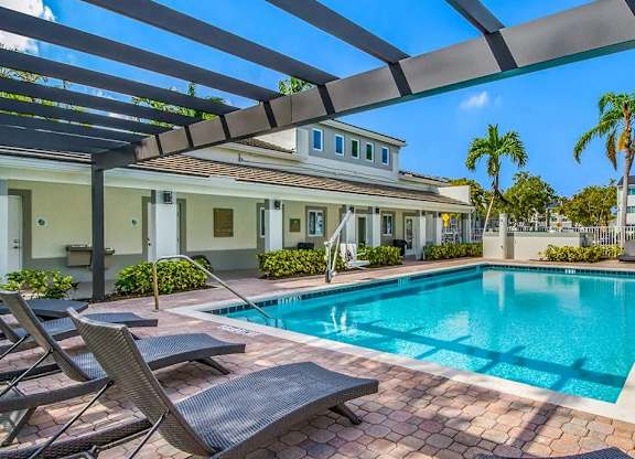 A pool with lounge chairs and a building in the background.