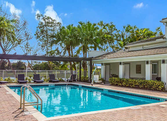 A swimming pool with a metal ladder and a house in the background.
