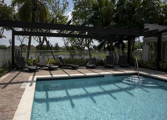 A pool with a black canopy and a brick border.