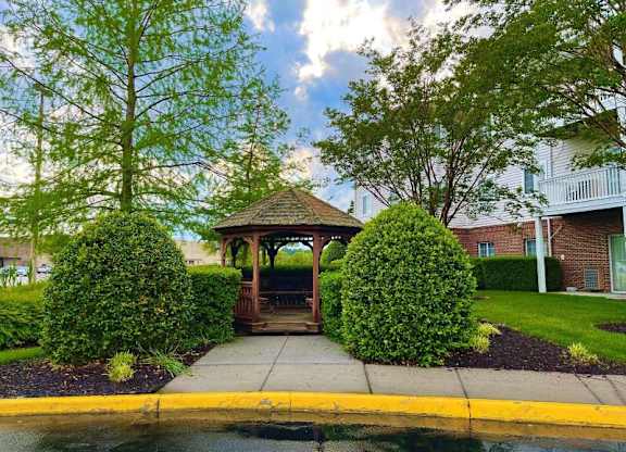 a gazebo in a yard with trees and bushes at Greenbrier Seniors Apartments, Chesapeake, VA  