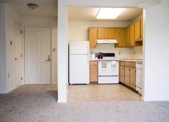 an empty kitchen with white appliances and wooden cabinets at Greenbrier Seniors Apartments, Chesapeake, Virginia  