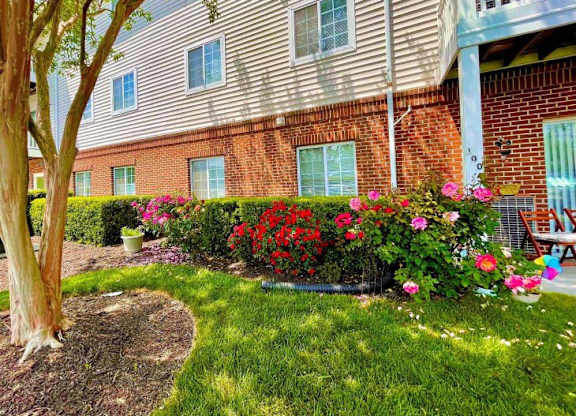 the front yard of an apartment building with flowers and grass at Greenbrier Seniors Apartments, Chesapeake 