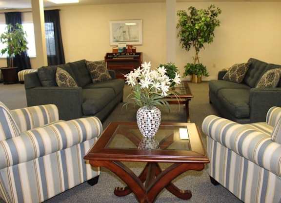 a living room with couches and a table with flowers at Greenbrier Seniors Apartments, Chesapeake, VA  