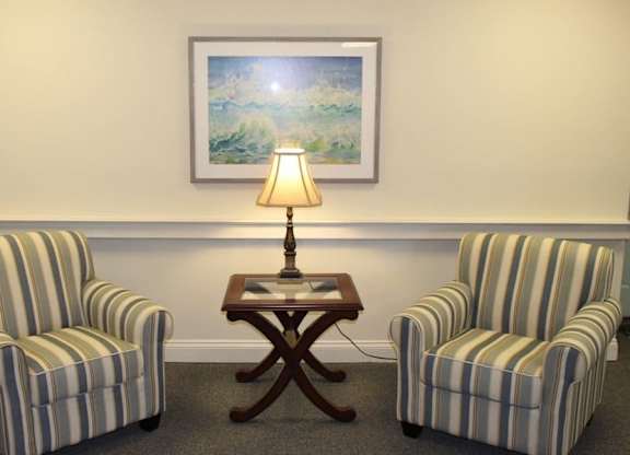 a living room with two chairs and a table with a lamp at Greenbrier Seniors Apartments, Chesapeake, 23320  