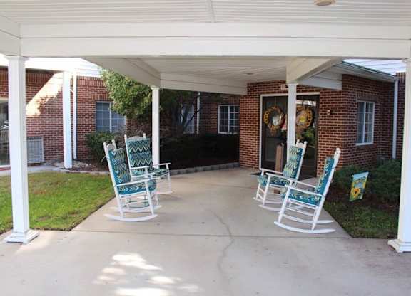 a group of rocking chairs sitting on a porch at Greenbrier Seniors Apartments, Chesapeake, Virginia  