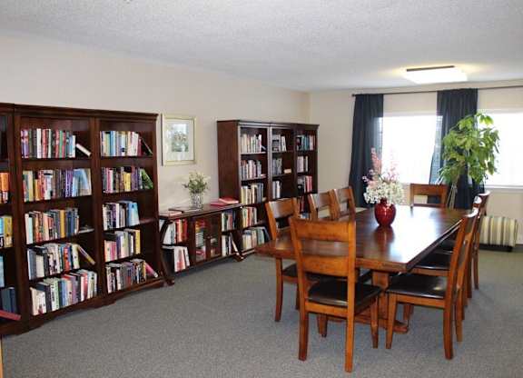 a dining room with a table and chairs and bookshelves at Greenbrier Seniors Apartments, Chesapeake, VA  