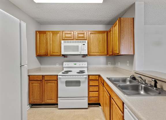 a kitchen with white appliances and wooden cabinets at Palms on Ashley River Apartments, Ladson