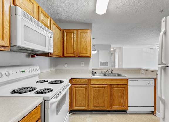 a kitchen with white appliances and wooden cabinets at Palms on Ashley River Apartments, South Carolina 29456