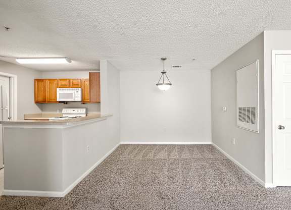 an empty kitchen and dining room with a white door and chandelier at Palms on Ashley River Apartments, Ladson, SC