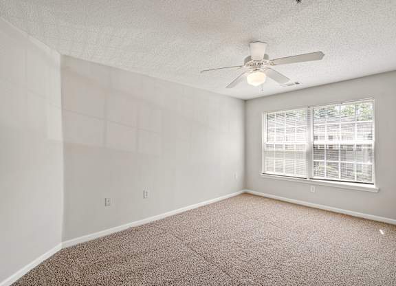 a bedroom with a ceiling fan and a window at Palms on Ashley River Apartments, Ladson, South Carolina