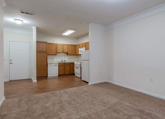 A kitchen with white appliances and wooden cabinets.