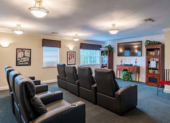 A living room with black leather chairs and a grey carpet.