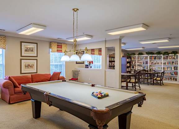 A pool table is in the middle of a room with a couch and a chair.