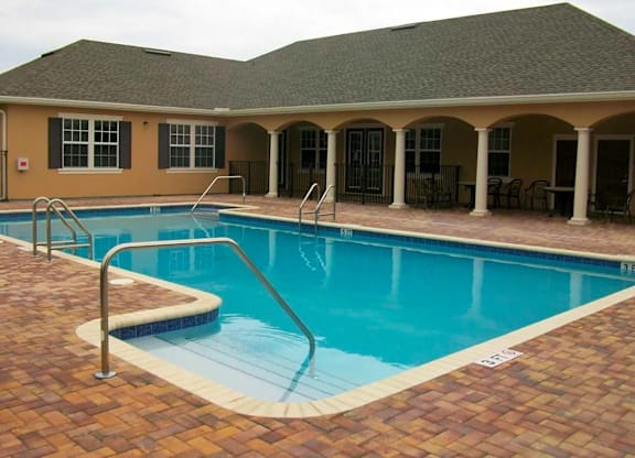 a swimming pool in front of a house with a resort style pool