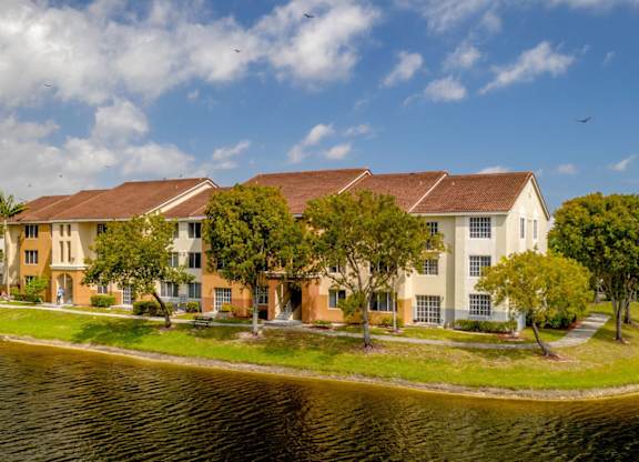 a group of apartment buildings on a grassy area next to a body of water