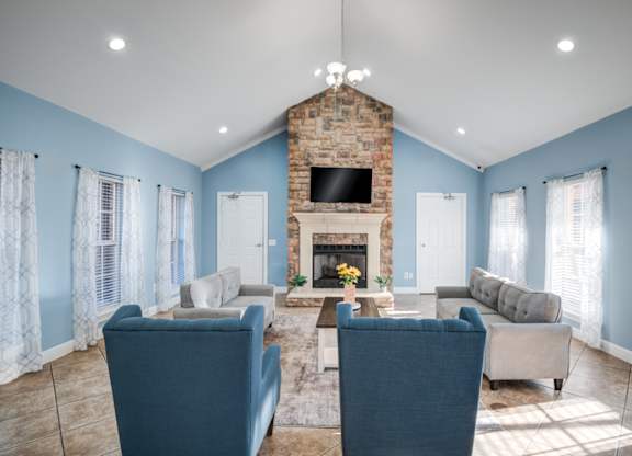 A living room with a fireplace and blue chairs.