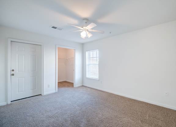 A room with a ceiling fan and carpeted floor.